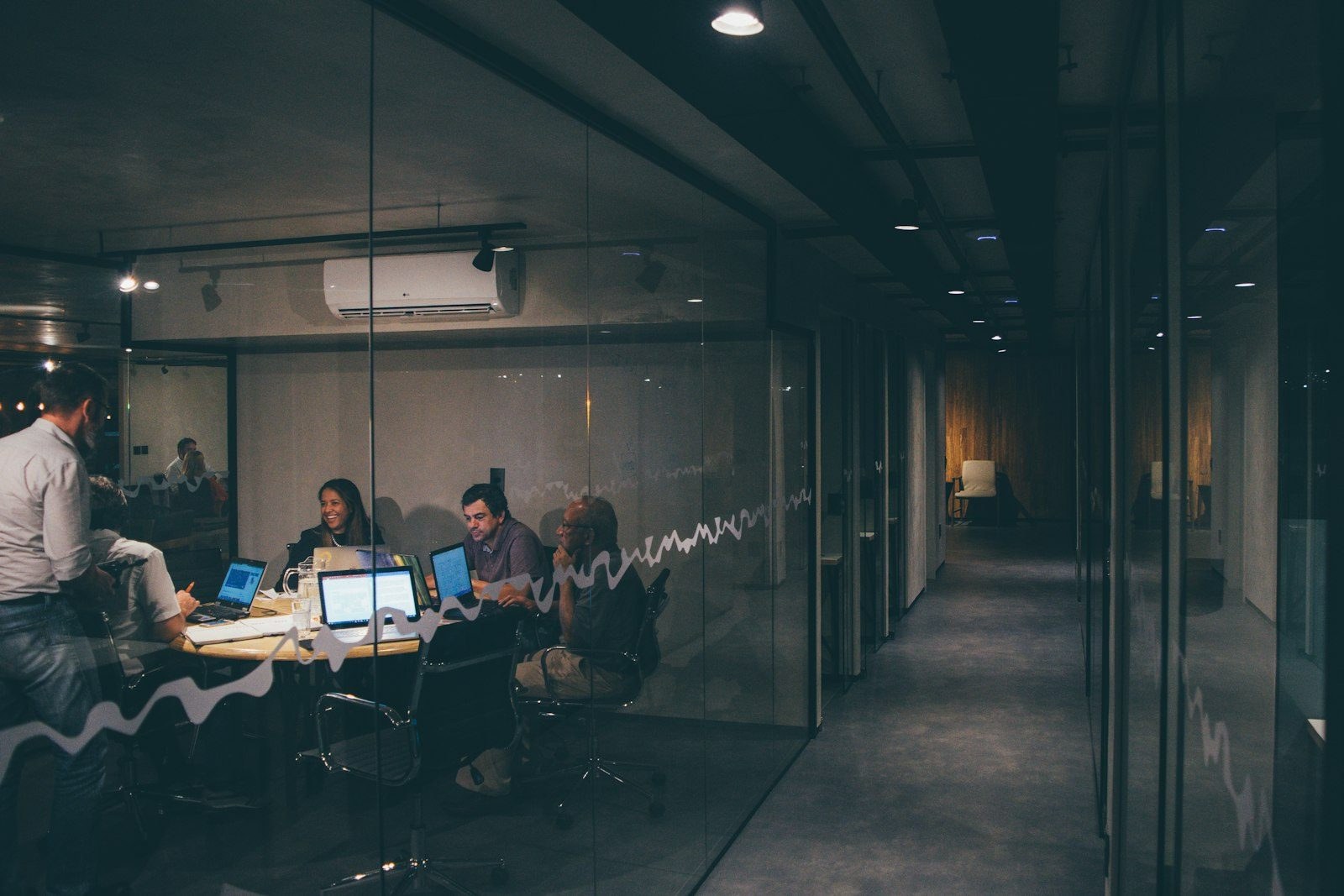 A glazed office corridor with a meeting under way