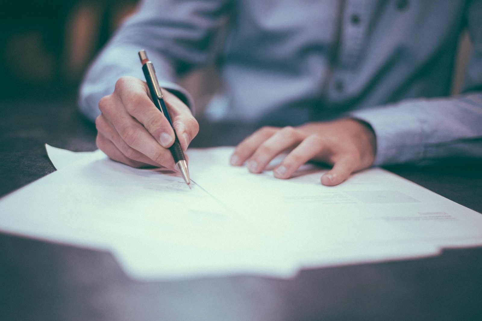 A hand signing a document at a desk